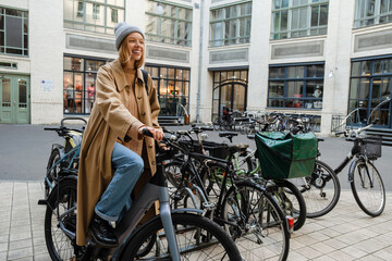 Fototapeta na wymiar Cheery blonde woman standing with bike outdoors