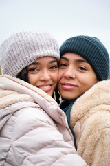 Dominican lesbian couple hugging with affection and love at street in a winter day.