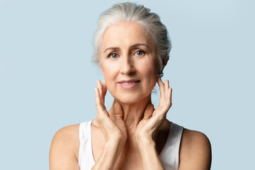 Beautiful senior woman with  gray hair takes care of her skin. A mature woman  is nursing herself