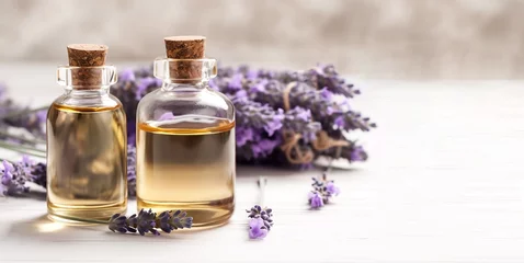 Tuinposter Bottles of essential oil for aromatherapy, alternative medicine or perfumery and a bouquet of fresh lavender on a light abstract background. Side view, close-up. © Алекс Ренко