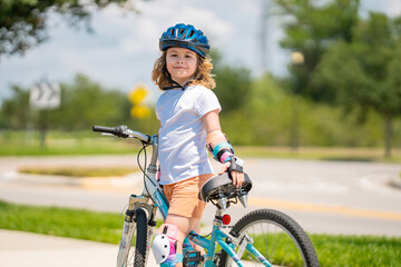 Child riding bicycle. Little kid boy in helmet on bicycle along bikeway. Happy cute little boy riding bicycle. Child in the protective helmet for bike cycling on bicycle.