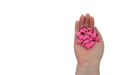 A handful of pink candies in the shape of a heart in a hand isolated on a white background