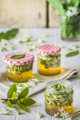 Pickled wild garlic blossoms on white wooden background, vertical