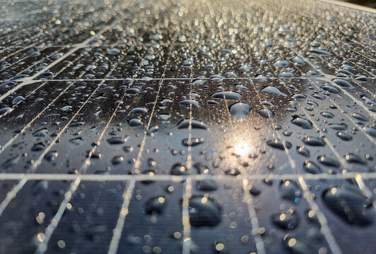 water drops on the surface of a photovoltaic solar panel with reflection of sun