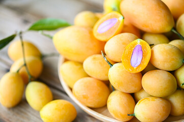 Naklejka na ściany i meble tropical fruit Name in Thailand Sweet Yellow Marian Plum Maprang Plango or Mayong chid, Marian plum fruit and leaves in plate on wooden background
