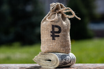 A bag for money with the symbol of the Russian ruble stands on a stack of banknotes in...
