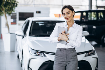 Young saleswoman with tablet in a car showroom