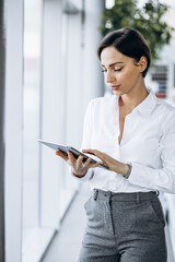 Young business woman holding tablet and smiling at the office