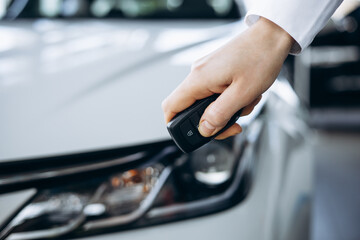 Woman holding car keys by her new car close up photo