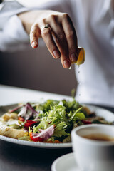 Woman squizing lemon on the salad