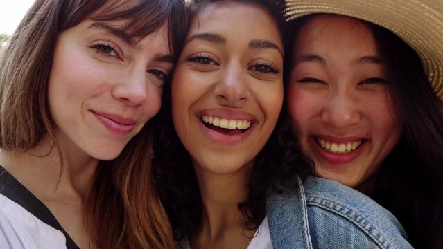 Young group of three diverse women smiling standing together outdoors. Joyful portrait of millennial female friends looking at camera hugging each other showing love and unity. Generative AI