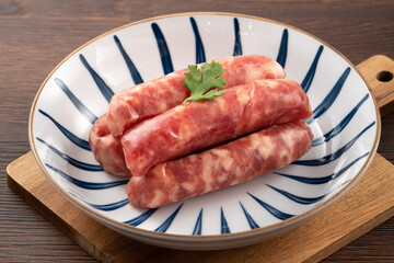 Raw Taiwanese sausage in garlic flavor in a plate on wooden table background.