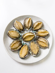 Delicious raw abalone in a plate on white table background.