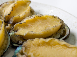 Delicious raw abalone in a plate on white table background.