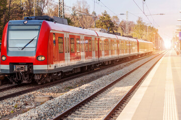 Fototapeta premium Electric Passenger Train on Railway Station. Modern Speed Train on Railroad Platform with Sun light.