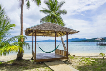 Tropical summer beach resort with palm, coconut trees, and hammock in Piugus Island, Anambas,...