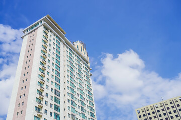 High-rise building photographed from below in the morning with clouds and blue sky background.