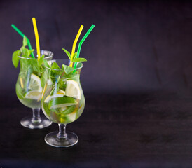 Summer mint lime refreshing cocktail mojito with ice in glass on black background copy space....