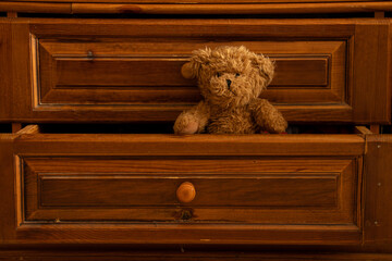 Teddy brown bear sits in a wooden pull-out old drawer in the bedroom as a background,furniture