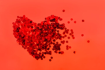 Red sequin in heart shape on red background. Valentine’s Day.