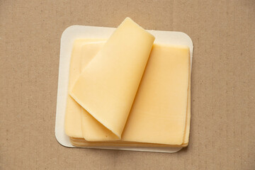 Slices of hard cheese lie on a brown cardboard , food