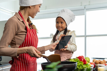 Happy Pretty mom and lovely daughter preparing healthy food in kitchen