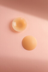 A pair of silicone sticker pad to cover nipples on pink background