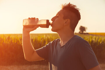 Man is drinking a water during the training outdoors.