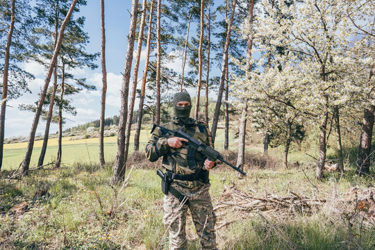 A Russian soldier spetsnaz with a Kalashnikov tactical assault rifle in a camouflage uniform in Ukraine's spring mountains.