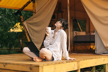 Happy young woman tourist sitting in touristic tent at summer time