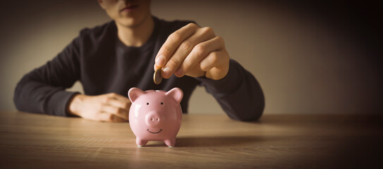 Young man with a piggy pank, takes care about his savings