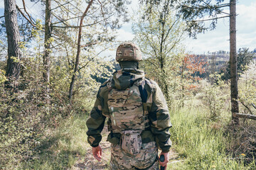 A special forces soldier guards the area. A soldier with an assault rifle in camouflage with tactical equipment. various camouflage