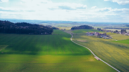 Green field, farmland with picturesque European landscape. Road in the middle of fields. Soft light. footage video drone view. in the background a range of mountains