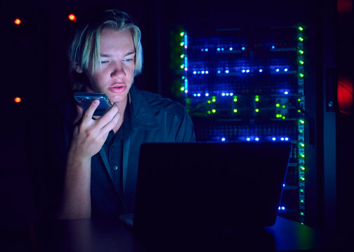 Technician using laptop and smart phone in server room