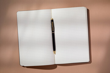 Pen in open notebook on brown background