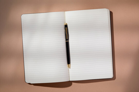 Pen in open notebook on brown background