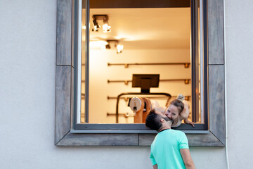 Couple in love. Boy standing outdoors kissing a girl from within a window.