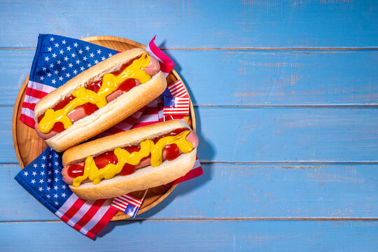 USA Patriotic picnic holiday hot dogs.  American patriotic hot dog on wooden board plate, with USA flag. Celebrating Independence day on 4th July, Memorial or Veteran Day
