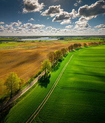 Warmia and Mazury - spring agricultural landscape Linowo near Olsztyn. Lake Linowskie in the distance - obrazy, fototapety, plakaty
