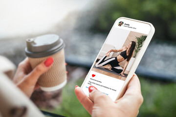 Woman looking at beautiful model's photo doing yoga on mobile phone