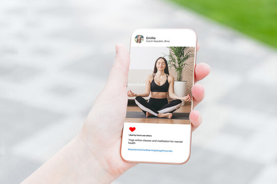 Woman looking at beautiful model's photo doing yoga on mobile phone