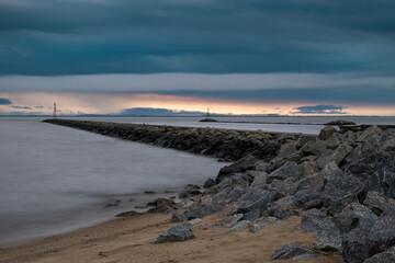 Rocky pier and threatening dark clouds during sunset at Playa Sere, Colonia, Uruguay