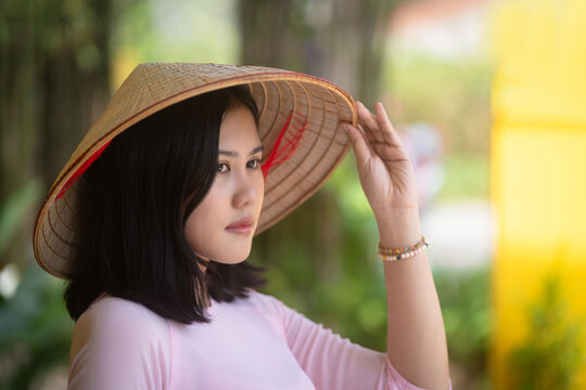 A pretty Vietnamese young Asian woman wearing an Ao Dai a traditional Vietnam dress national costume color pink Ao Dai is popular in Hoi An Old Town, Quang Nam, Vietnam.