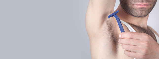 Caucasian man with disposable razor shaving his armpit.