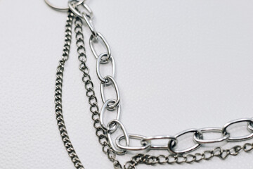 Different silver metal chains on a light background.