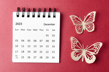 A December 2023 desk calendar for the organizer to plan and reminder with paer butterfly on red background.