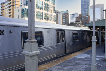 Subway train at platform with apartment highrises behind on cold day - 598319234