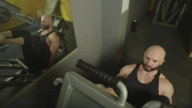 A man trains his legs on an exercise machine in the gym. Handsome muscular Caucasian man doing sports training body doing workout exercises. High quality 4k footage Generative AI