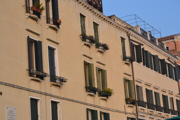 Fototapeta na wymiar Exterior facade of a building in Venice Italy painted yellow with long windows