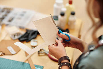 Hands of woman cutting out cardboard patterns for her new project